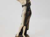 une image représentant une statue d'une femme en robe posée sur un socle en bois
