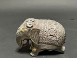 an old silver elephant figurine sitting on top of a table