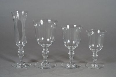 four wine glasses and a vase on a table with a gray background
