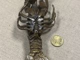 une petite statue en bronze représentant un homard, posée sur une table