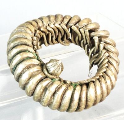 a gold bracelet with a bird on it on a clear surface