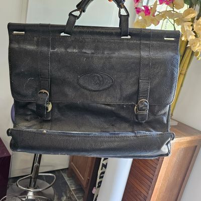 un sac noir posé sur un tabouret, à côté d'un vase de fleurs