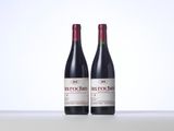two bottles of red wine sitting on top of a table