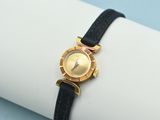 a gold watch on a black band on a napkin