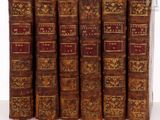 six vieux livres sont alignés sur une table