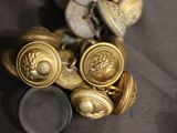 a pile of gold buttons and a magnifying glass on a table