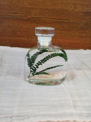 a glass bottle with a plant inside of it on a towel