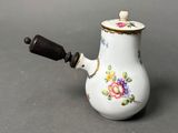 a small white tea pot with a flower design on it