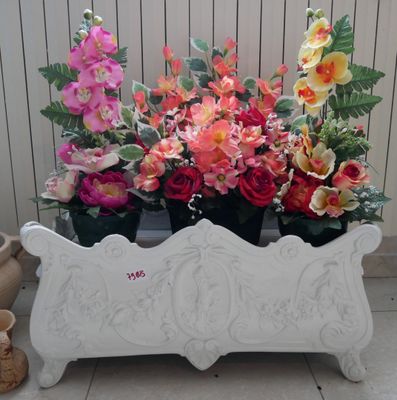 une jardinière blanche posée par terre et remplie de fleurs