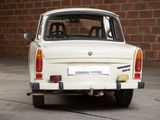 a small white car that is parked in front of a brick wall
