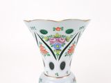 un vase blanc avec des fleurs sur une surface blanche