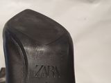 a close up of a person ' s hand holding a pair of black shoes