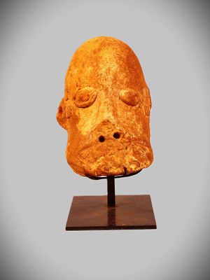 a close up of a sculpture of a head on a wooden stand