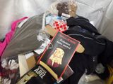 a pile of clothing and a book on a bed