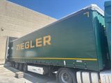 a large green semi truck parked in front of a building