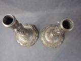 two silver candlesticks that are on a table