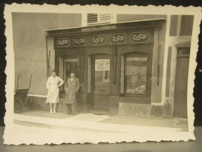 an old black and white photo of two people standing outside of a store