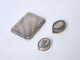 a small silver object next to a coin on a white surface