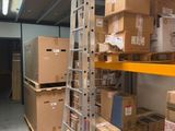 Les cartons sont empilés sur des étagères dans un entrepôt équipé d'une échelle