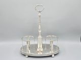 an antique silver plate with three glasses and a candle holder