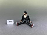 a figurine of a man sitting on the ground next to a sign