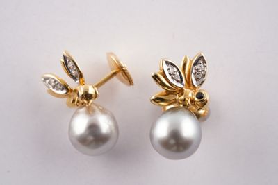 deux paires de boucles d'oreilles en perles et diamants posées sur un fond blanc