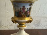 a vase with a painting on it sitting on a table