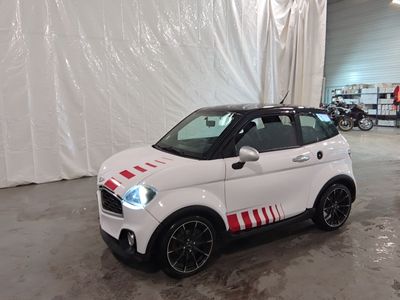 une petite voiture blanche avec des bandes rouges, garée dans un garage