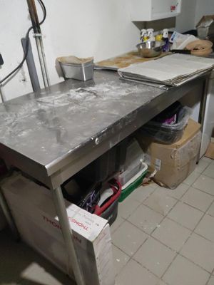 table de travail en acier inoxydable dans une cuisine professionnelle très encombrée