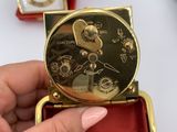a person holding a gold clock in a red box