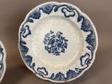 two blue and white plates with floral designs on them sitting on a table
