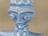 a blue ceramic figurine of a woman with a hat on her head