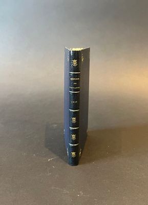 an old blue book sitting on top of a table next to a gray wall