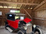 une vieille voiture dans un garage avec une pancarte sur la porte