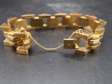 a close up of a gold bracelet on a table with a chain