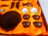 an orange box with chocolate eggs and spoons in it