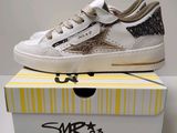 une paire de baskets blanches ornées de paillettes noires et dorées