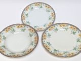 three plates with yellow flowers on them sitting on a white surface
