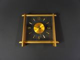 a gold clock on a black wall with a black background