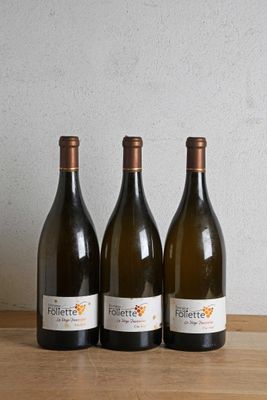 three bottles of wine are lined up on a wooden table