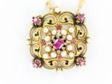 a close up of a gold necklace with a pink stone and pearls