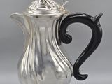 a silver coffee pot with a black handle and a black handle