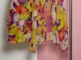 deux vêtements suspendus à un portant devant un mur rose