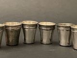 six silver cups are lined up in a row on a table