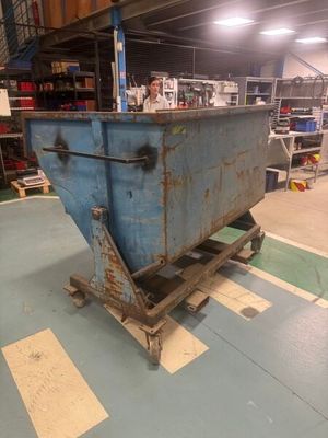 a blue dumpster sitting on a pallet in a warehouse
