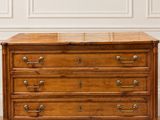 une commode ancienne posée sur un parquet dans une pièce blanche