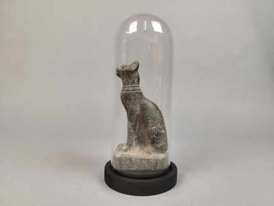 statue d'un chat assis sous un dôme en verre, posée sur un socle noir