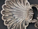 a silver plate with a shell on it on a black surface