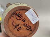 a person holding a bottle with arabic writing on it