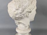 a white marble bust of a woman on a pedestal on a gray background